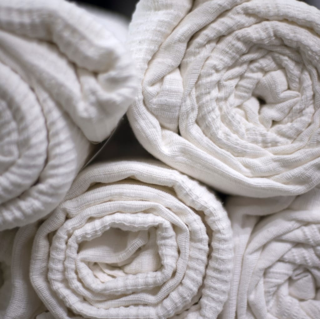 Close-up view of multiple rolled white muslin cotton fabric strips bundled together, showcasing their soft, textured surface.