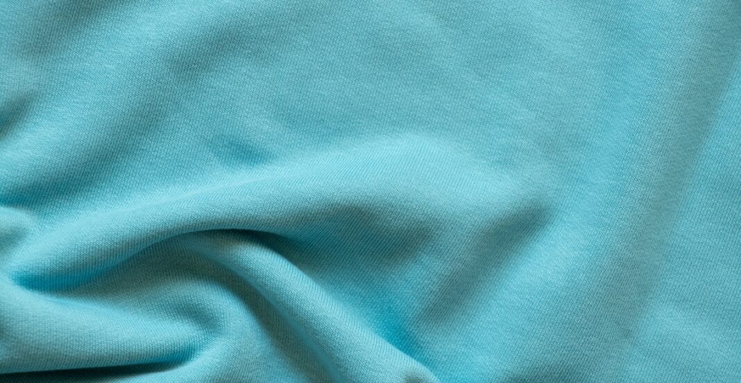 A close-up image of plain weave cotton fabric showing a smooth, lightly textured surface in a light turquoise color.