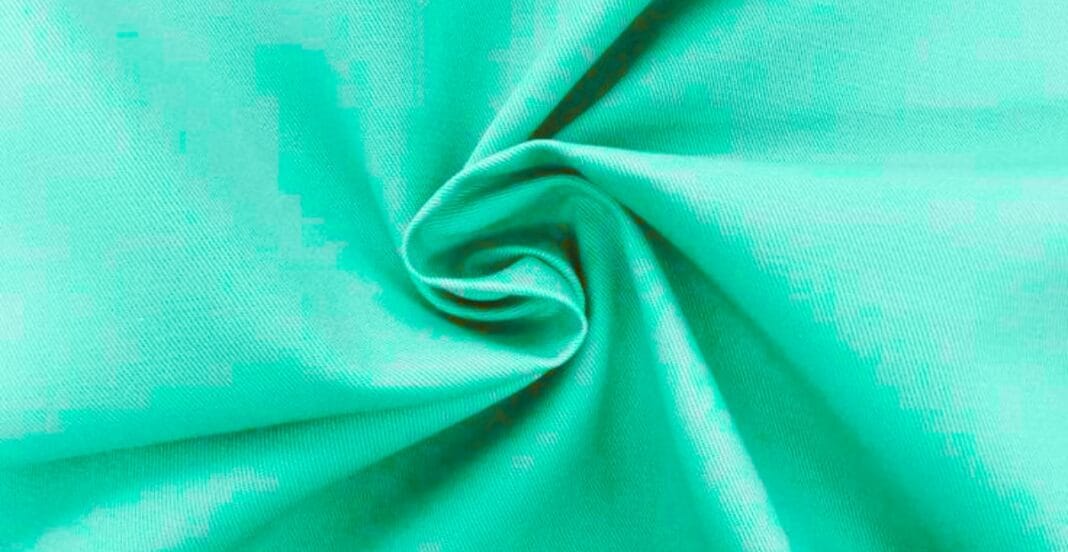 A close-up image of turquoise polyester fabric draped and twisted to showcase its smooth texture and sheen.