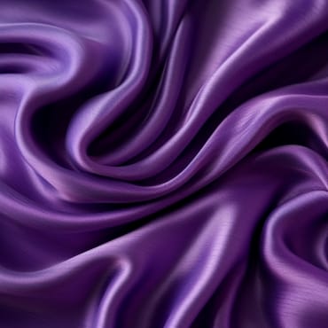 Close-up of shiny, purple polyester silk blend fabric with smooth, flowing folds.