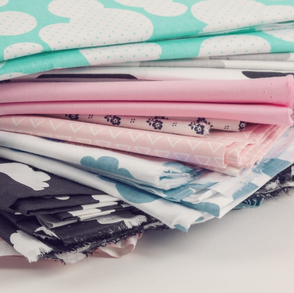 Several folded pieces of colorful cotton fabric stacked on top of each other, showcasing different patterns and textures.
