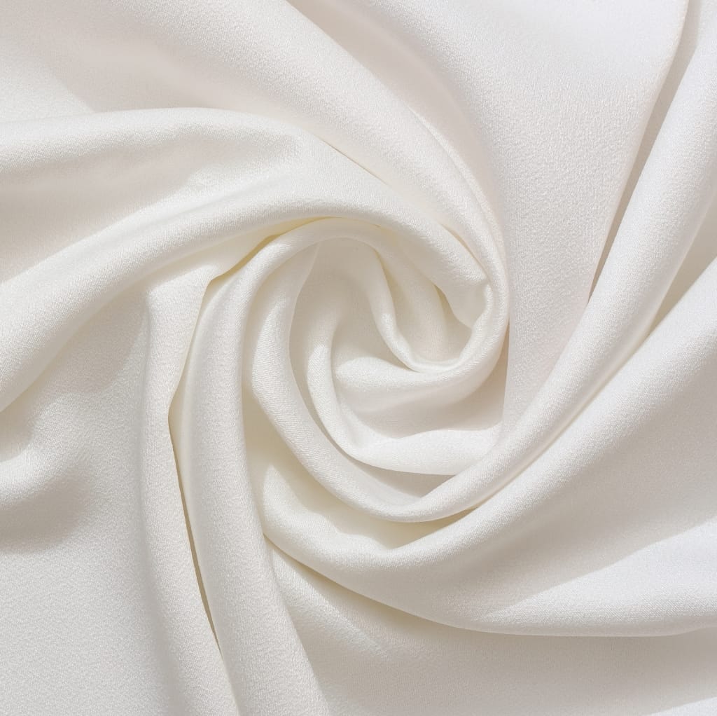 Close-up image of elegant, cream-colored satin fabric softly twisted into a spiral, showcasing its luxurious texture and sheen.