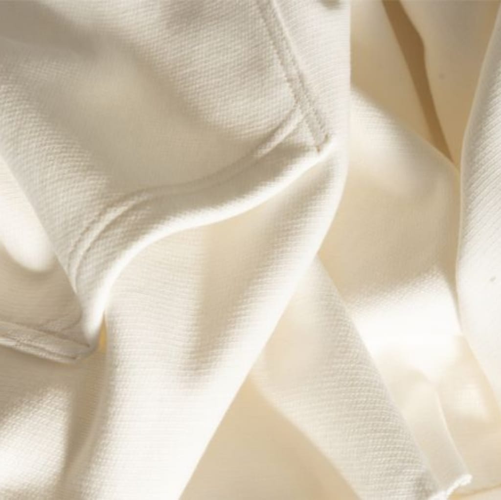 Close-up photo of cream-colored, textured fabric with visible stitching, showcasing a smooth, durable, and high-quality material.
