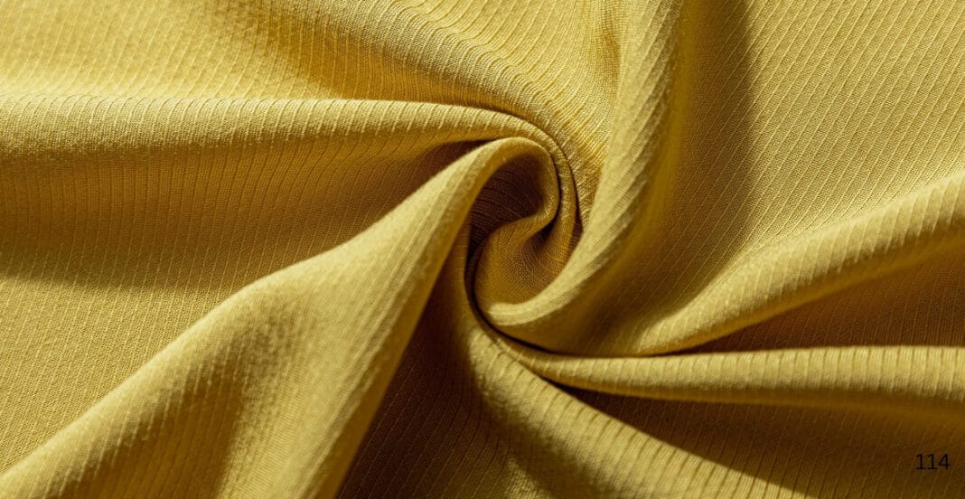 A close-up image of folded gold-colored twill cotton fabric, showing its diagonal weave pattern.
