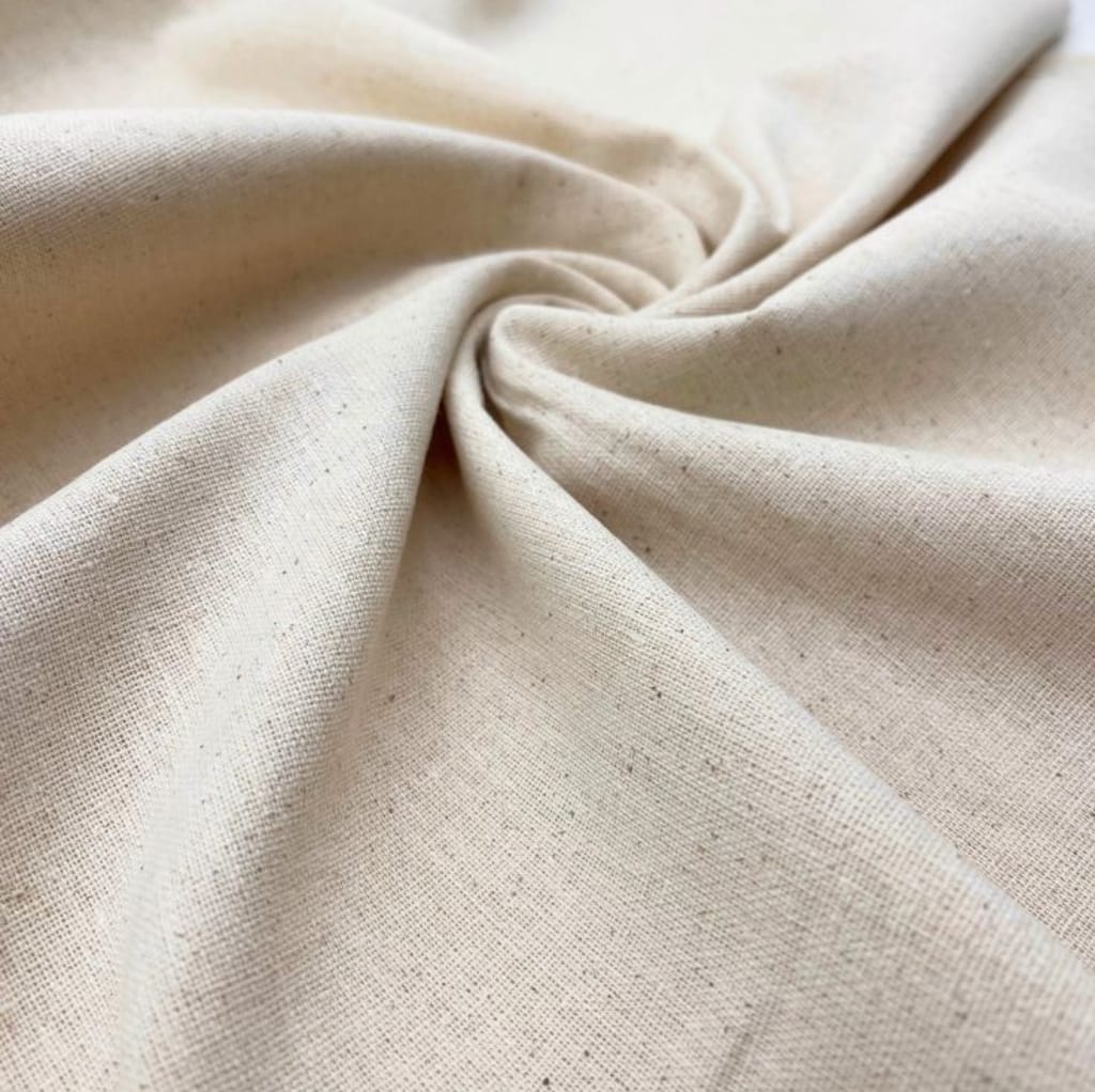 A close-up image of beige or natural-colored cotton fabric, gently twisted in the center, showcasing its soft texture and weave pattern.