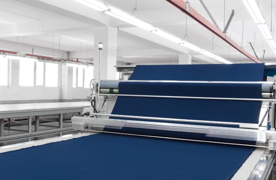 A modern cotton fabric production machine in a clean, well-lit factory, showcasing the manufacturing process.