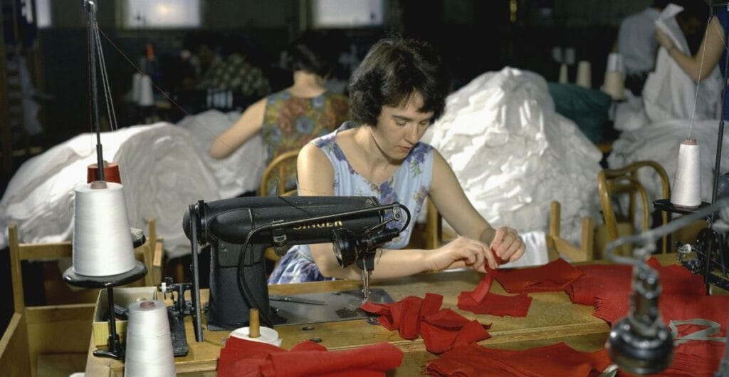 Woman sewing red fabric in a textile factory with a vintage sewing machine_____What Performance Fabrics Are Really Made Of