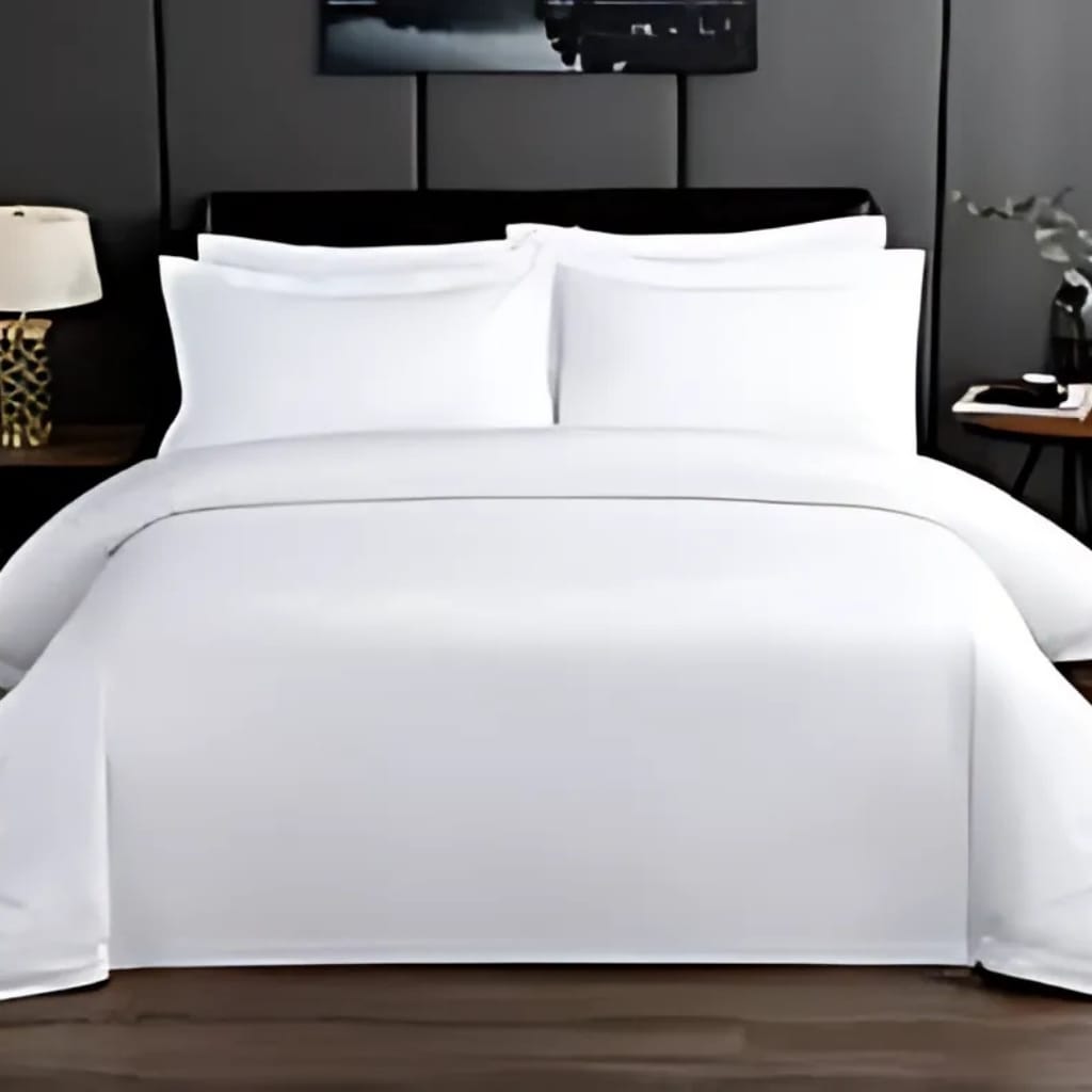 A neatly made bed with white bedding, pillows, and sheets in a modern bedroom. The bed has a black headboard, with dark-colored walls behind it. On each side of the bed, there are nightstands, with a lamp on the left and a plant on the right.