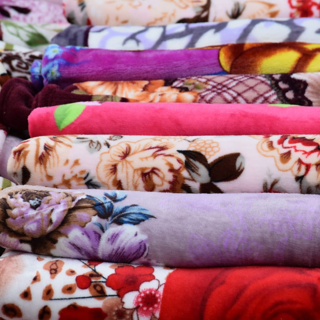 A neat stack of colorful, floral, and patterned fabric rolls arranged side by side.