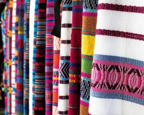 Close-up view of colorful woven fabrics hanging on a rack, showcasing various patterns and textures.
