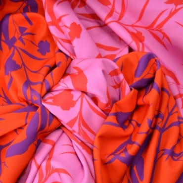 Close-up image of vibrant, colorful fabric with a floral pattern featuring shades of pink, orange, and purple.