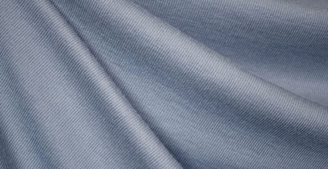 Close-up image of light blue double-knit polyester fabric with a fine, smooth texture and subtle diagonal ribbing.
