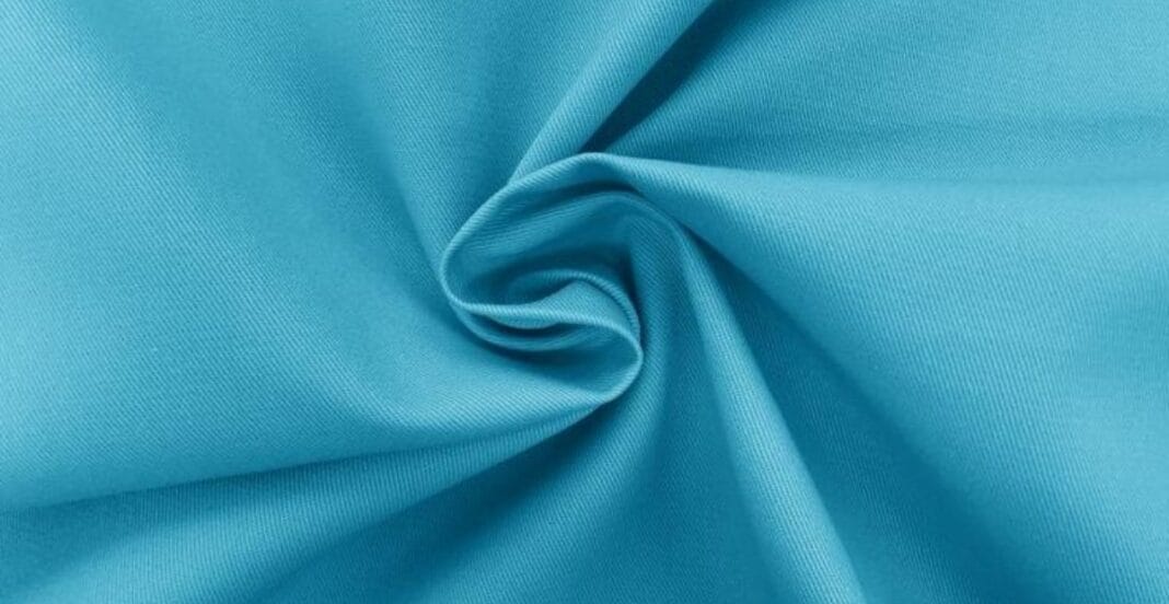 A close-up image of smooth, light blue polyester fabric gently twisted, showcasing its texture and lightweight nature.
