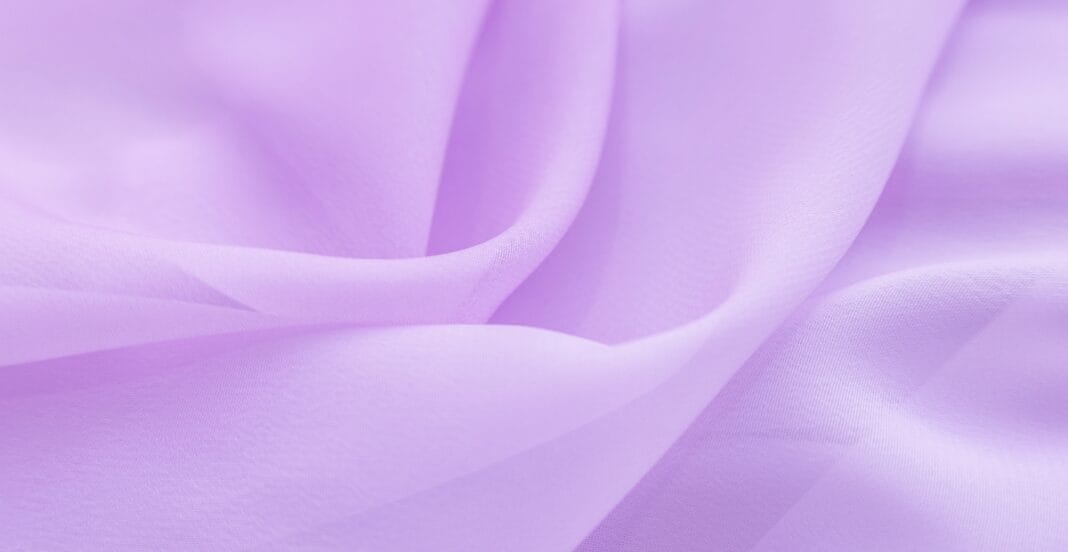 Close-up of soft, light lavender lightweight cotton fabric with gentle folds and a smooth texture.
