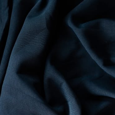 Close-up of dark navy polyester-linen blend fabric with soft folds and a slightly textured surface.