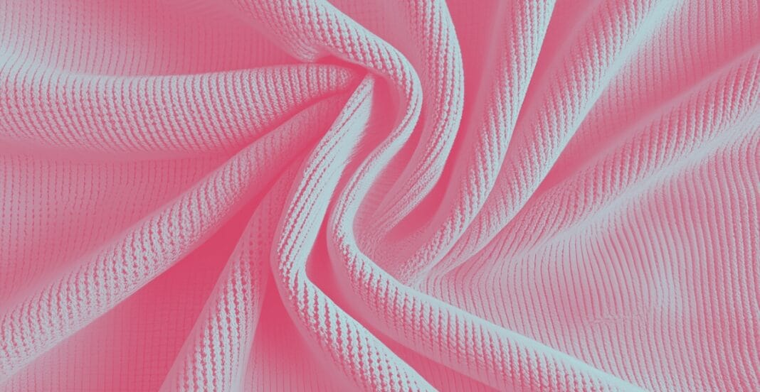 Close-up view of pink polyester pique knit fabric with textured, patterned surface and soft folds.