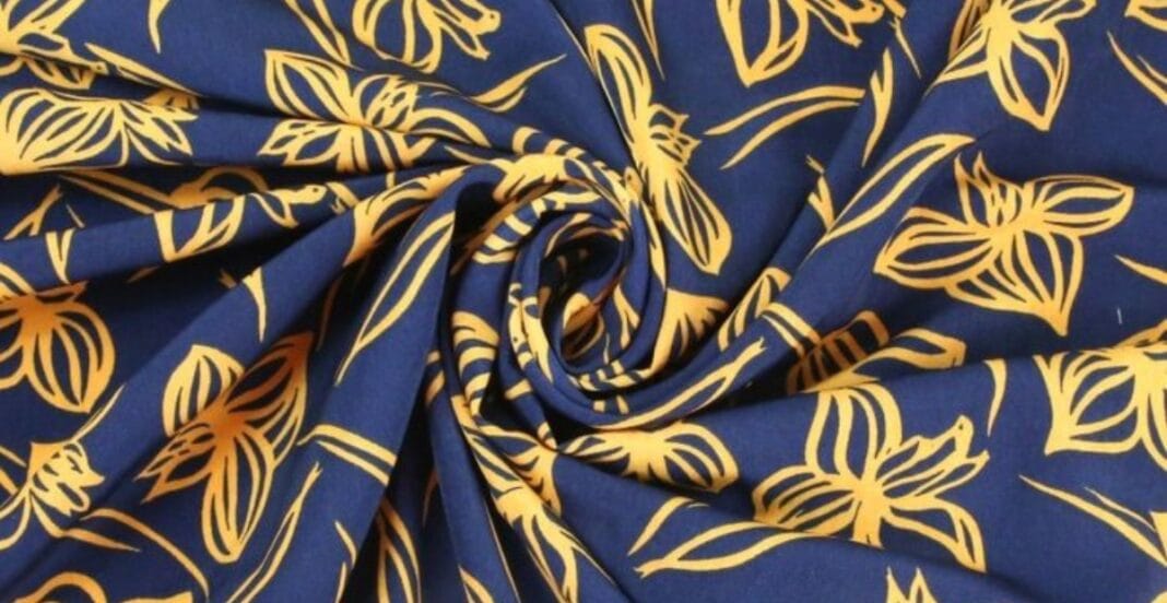 Close-up of blue polyester fabric with a yellow floral print design, arranged in a spiral pattern.
