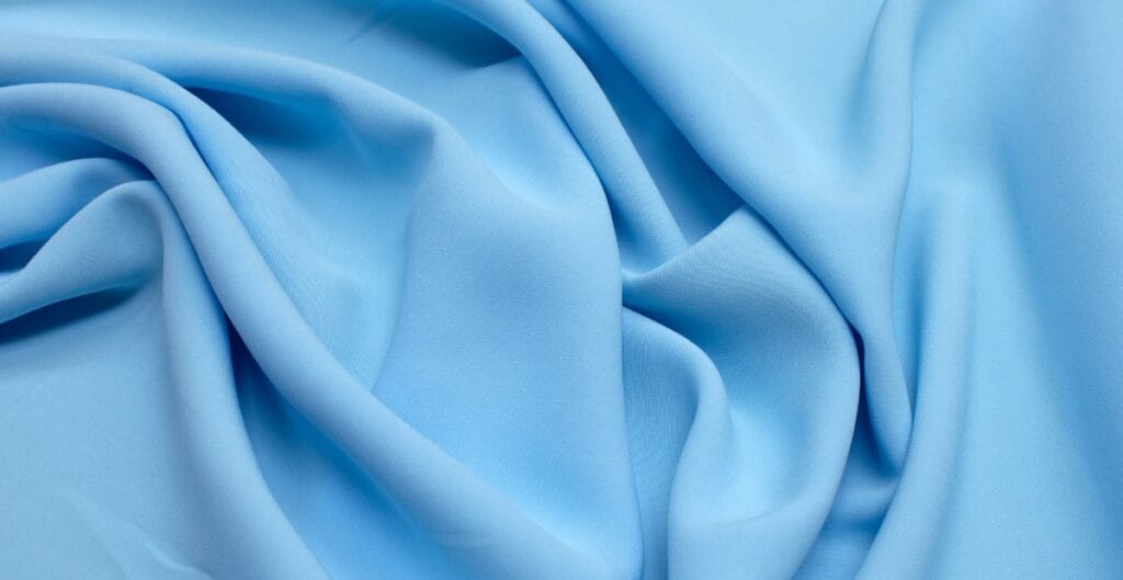 Smooth, light blue fabric with soft folds and gentle ripples.