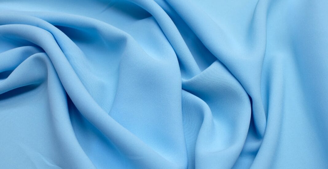 Smooth, light blue fabric with soft folds and gentle ripples.