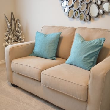 A beige sofa with two light blue cushions in a cozy, well-decorated living room.