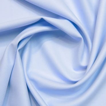 Close-up of light blue polyester fabric with gentle folds and a smooth texture.