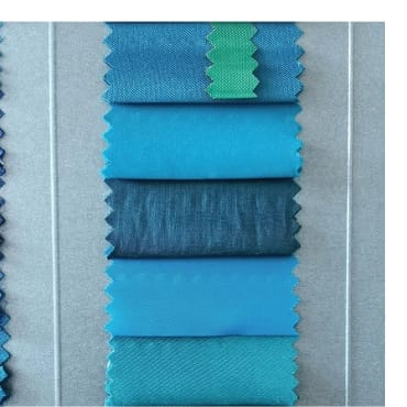 Color swatches of brushed polyester fabric in various shades of blue and green displayed on a fabric sample board.
