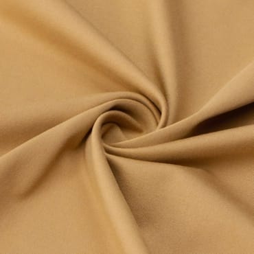 Close-up of beige polyester spandex fabric twisted into a spiral.
