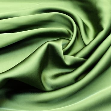A close-up image of smooth, light green satin-like fabric with folds, showcasing its shiny and soft texture.