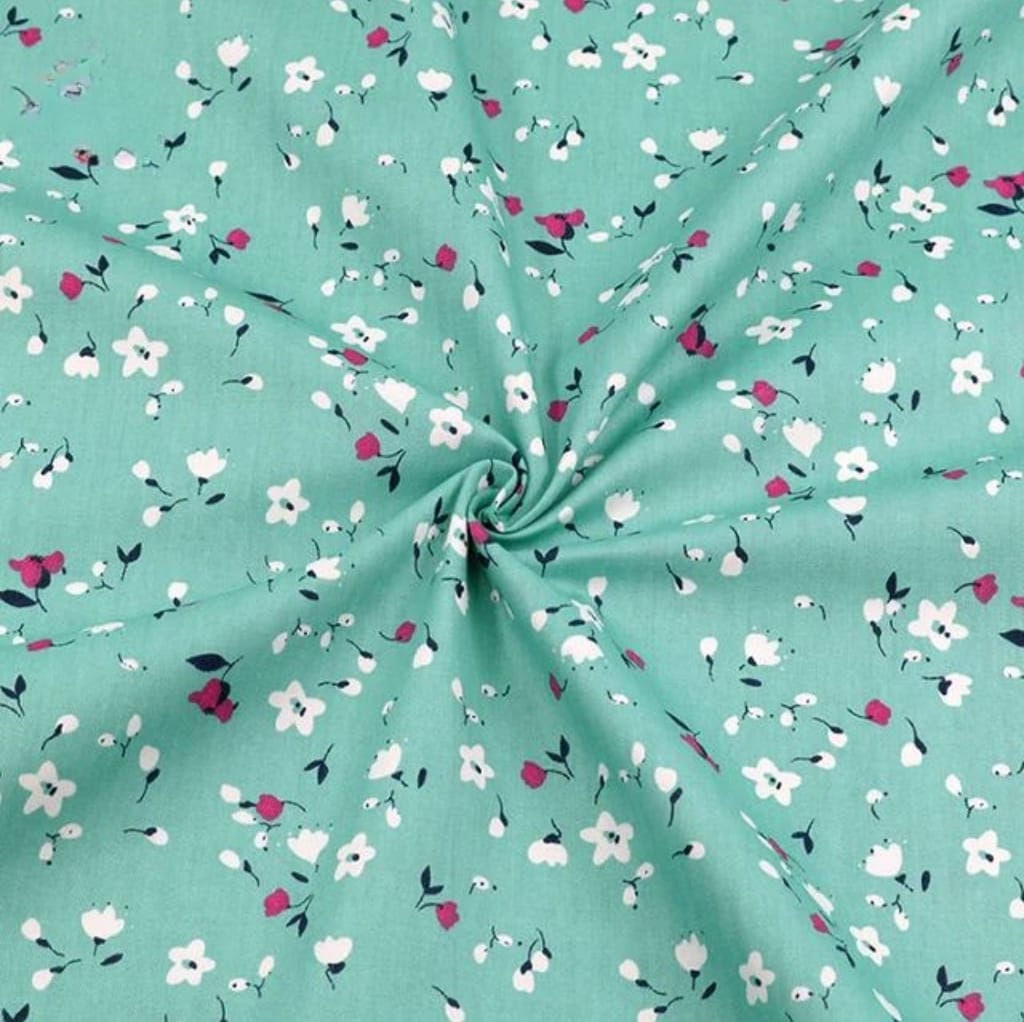 A close-up image of a soft, lightweight cotton lawn fabric featuring a mint green background with small, scattered floral prints in white, pink, and dark green.