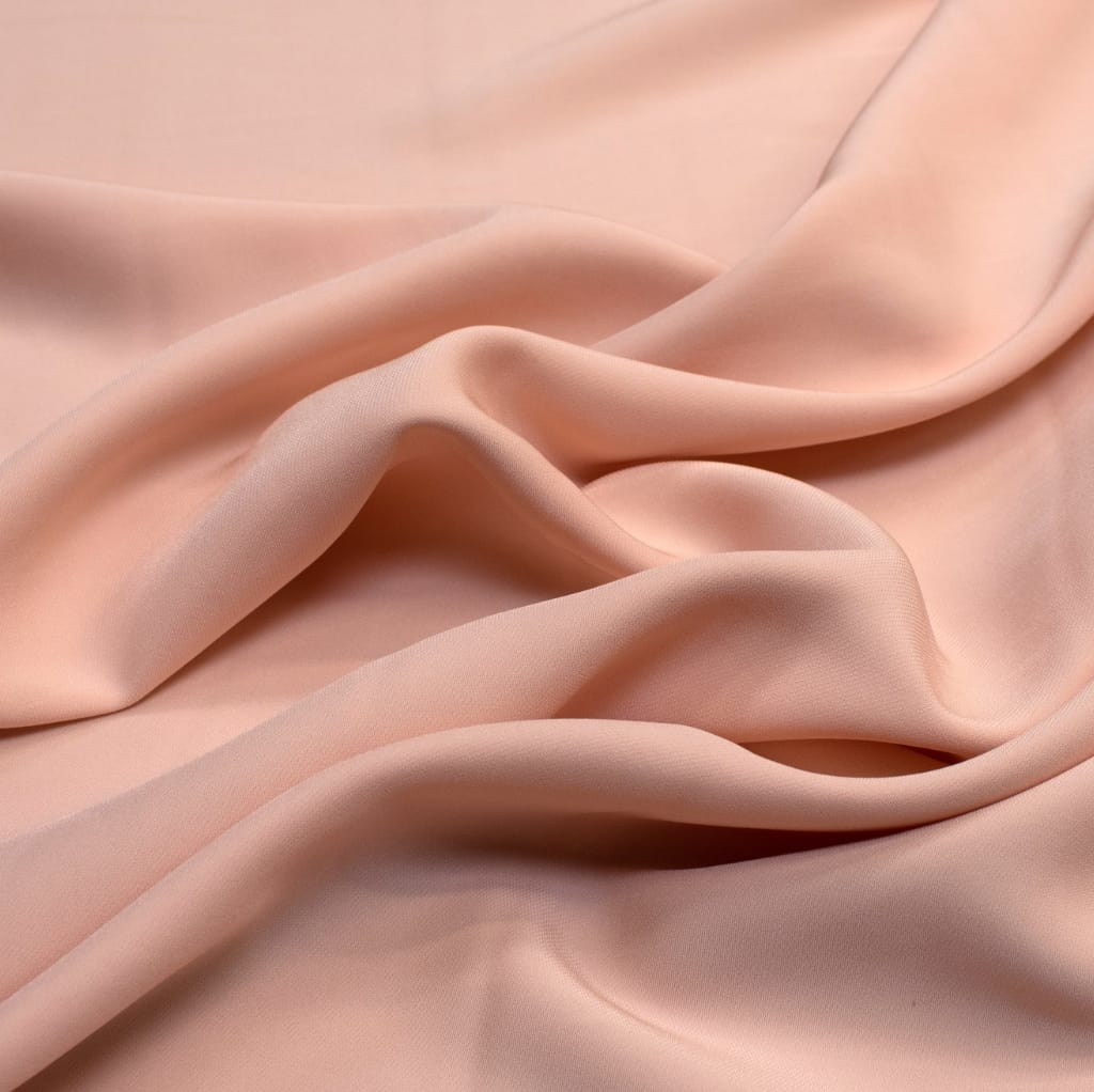 Soft, blush pink cotton fabric with gentle folds, showcasing its smooth texture and lightweight drape.