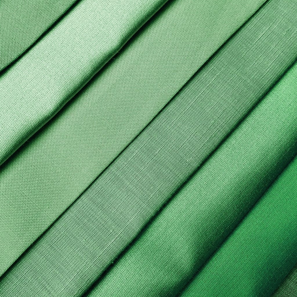 Close-up of vibrant green velvet fabric with a smooth, luxurious texture, showing folded panels with fine weave details.