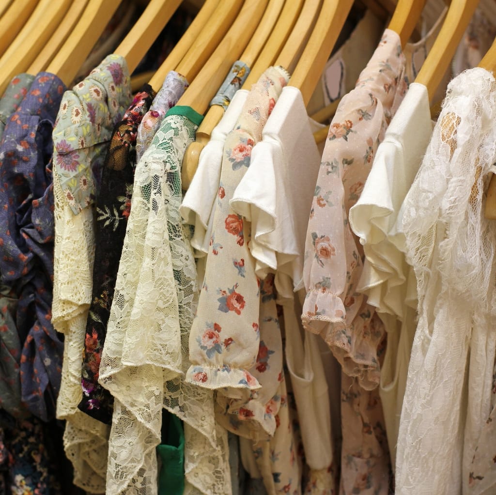 A row of hanging summer cotton dresses with various colorful prints and lace details, showcasing a range of pastel, floral, and vibrant patterns.