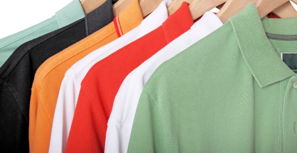 A row of colorful polo shirts hanging on a rack, including colors like black, orange, white, red, and light green.