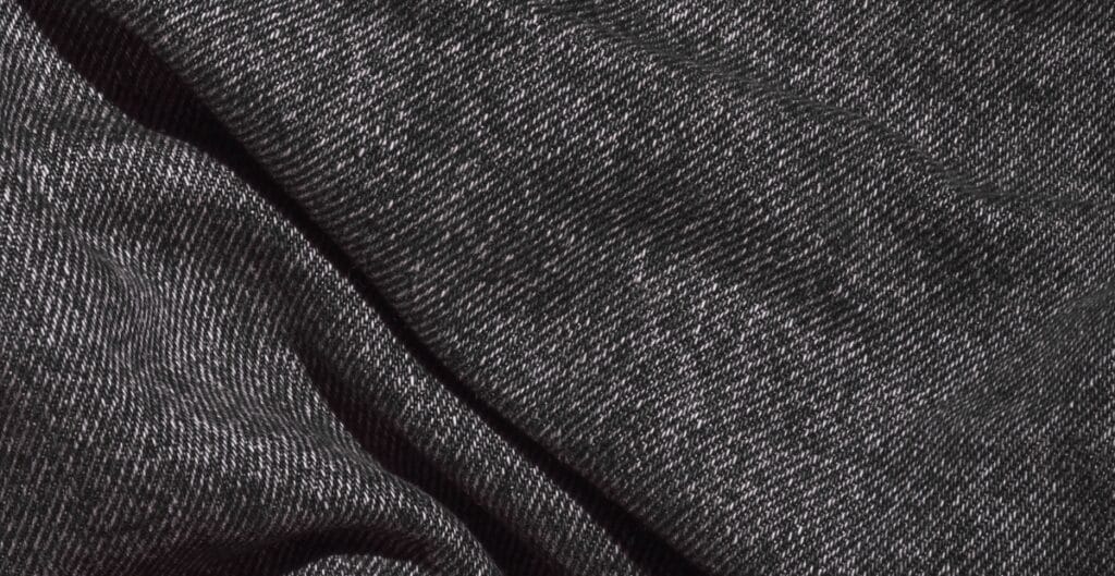 Close-up image of black denim fabric with a fine diagonal weave pattern.