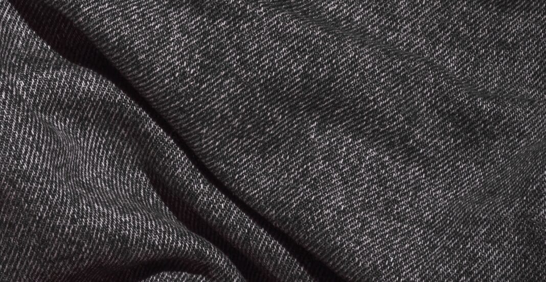 Close-up image of black denim fabric with a fine diagonal weave pattern.