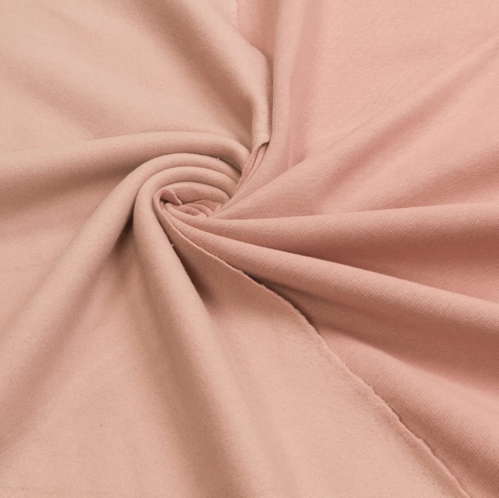 Close-up of soft, light pink brushed cotton fabric twisted in the center, showcasing its smooth texture and gentle folds.