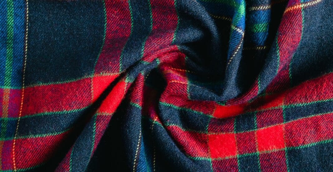Close-up image of a piece of brushed cotton fabric with a tartan plaid pattern in red, green, and navy blue colors.