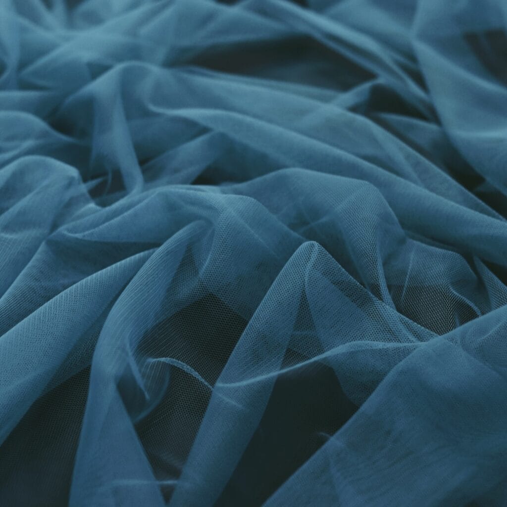A close-up photograph of crumpled blue sheer fabric with soft folds and a slightly transparent texture.