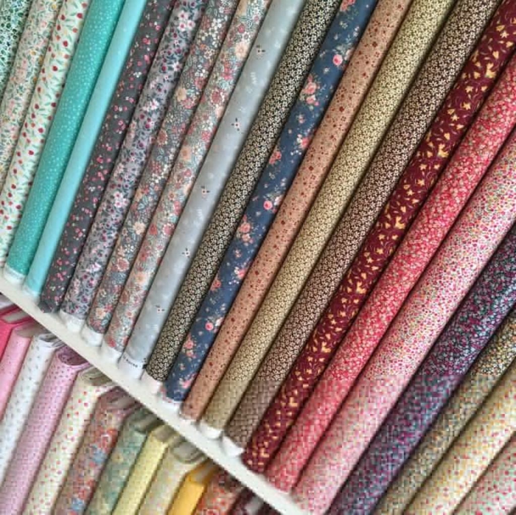 A selection of folded cotton print fabrics in various colors and floral patterns laid out on a display.