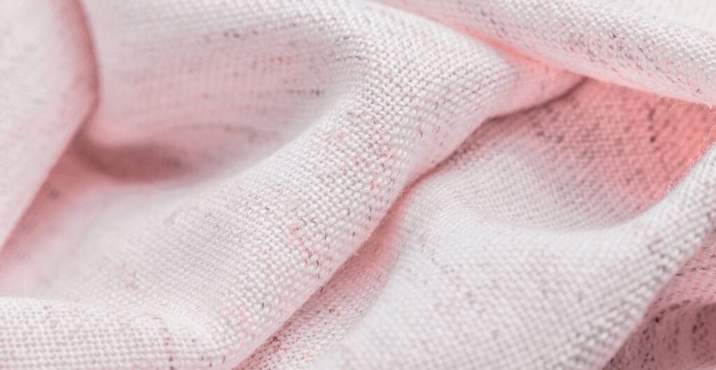Close-up image of coarse, lightly textured pink cotton fabric with visible weave and fibers