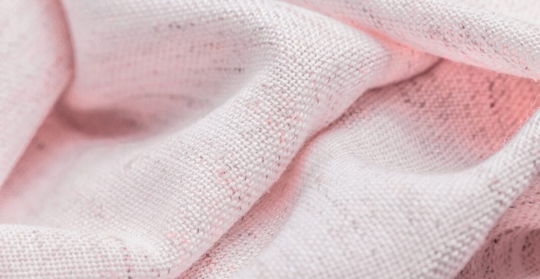 Close-up image of coarse, lightly textured pink cotton fabric with visible weave and fibers