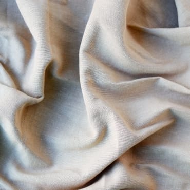 Soft, natural-colored cotton chiffon fabric with gentle folds and a smooth texture.
