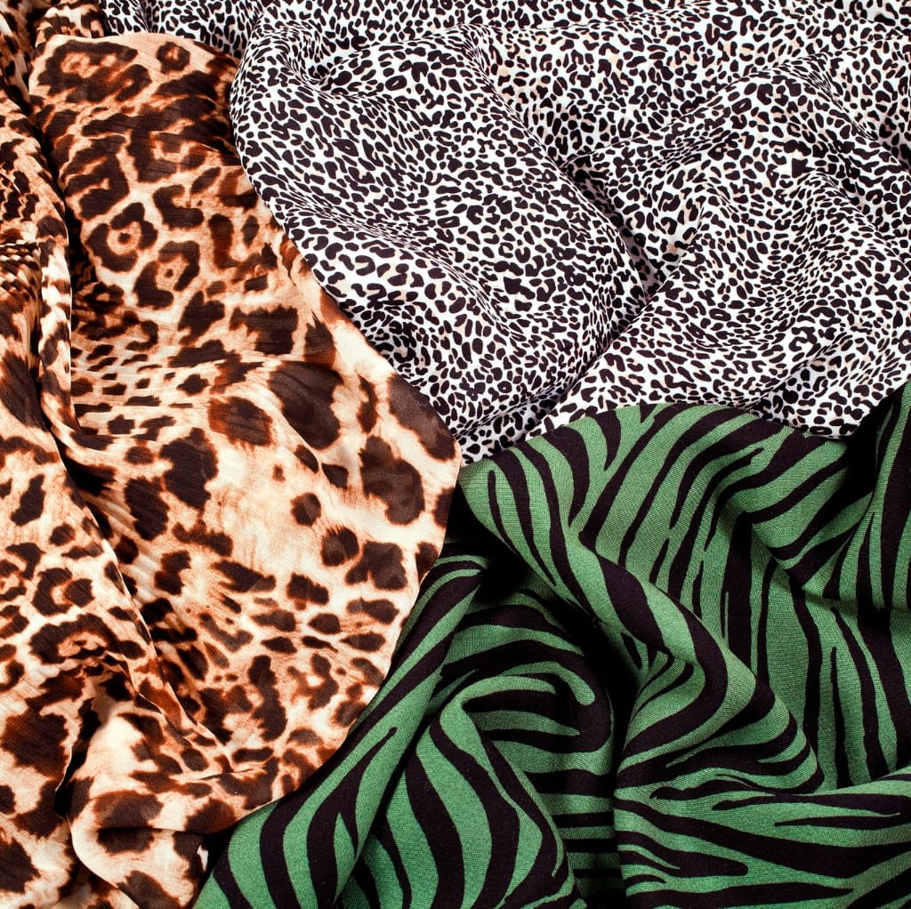 Close-up image of vibrant printed fabrics with animal patterns, including leopard, cheetah, zebra prints in various colors.