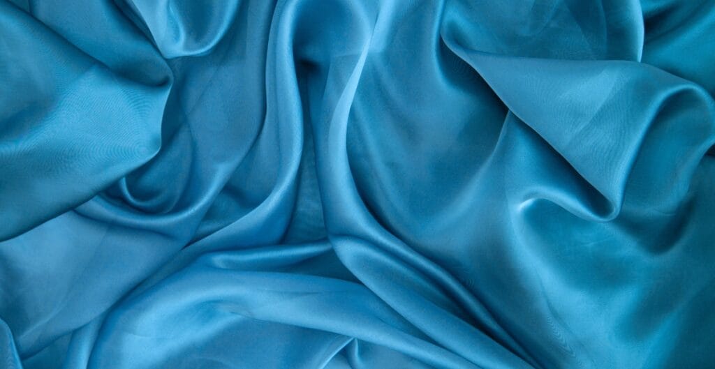 Close-up of blue crystal organza fabric with soft folds and a sheer, delicate texture.