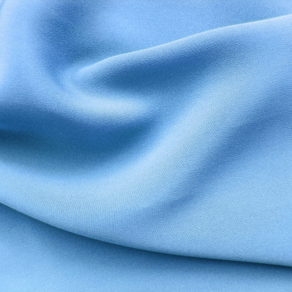Close-up of smooth, light blue fabric with a soft, matte finish and gentle folds.