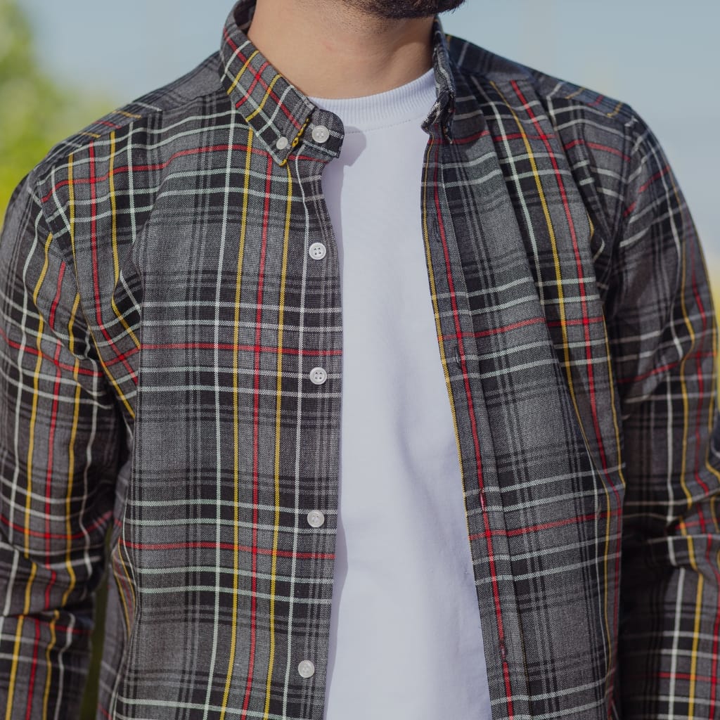 Close-up of a man wearing a classic plaid guayabera shirt over a white t-shirt, outdoors on a sunny day.
