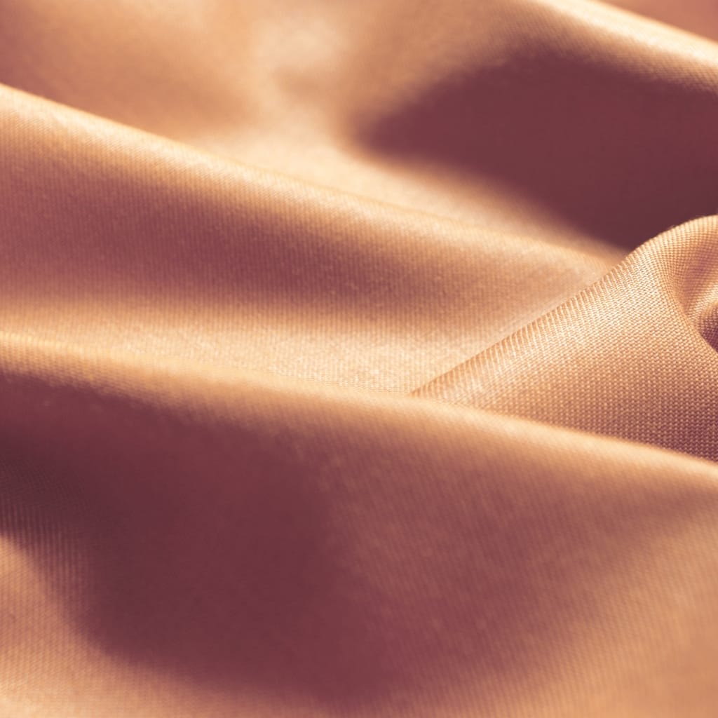 A close-up image of smooth, shiny fabric with a soft peach or light tan hue, showcasing its fine texture and subtle sheen.