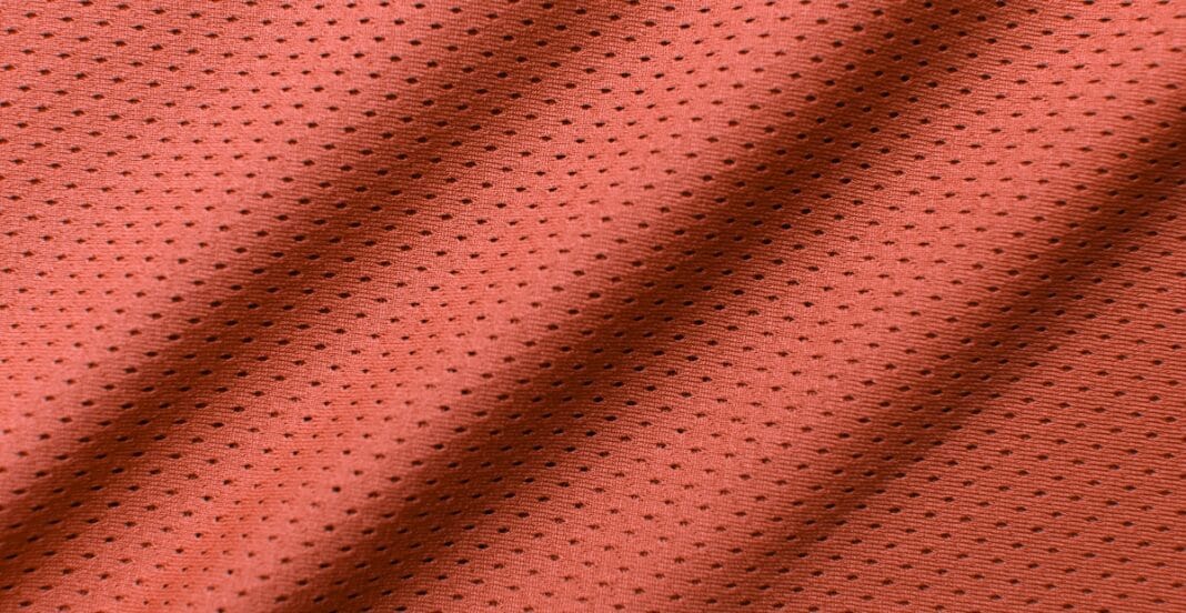 Close-up image of red mesh spandex fabric showing its perforated, breathable texture with small black dots.