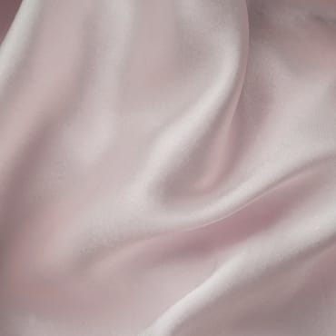 Close-up image of soft, light pink modal-spandex fabric with gentle folds and a smooth, silky surface.