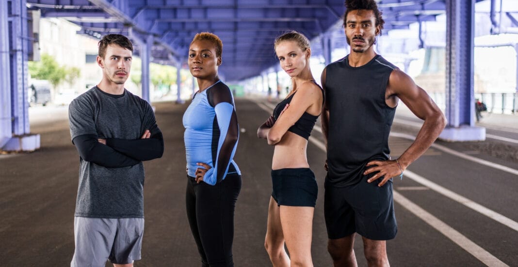A diverse group of four athletic individuals standing under a bridge, dressed in Nike sportswear, with confident expressions.